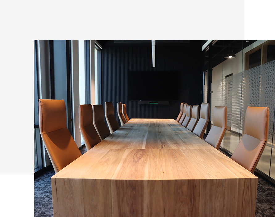 Modern conference room with a natural wood table and high-back leather chairs, designed with clean lines and a contemporary aesthetic.